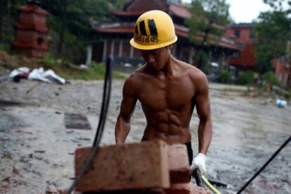 Worker Shi Shenwei pulls a wheelbarrow at the construction site of a Buddhist temple in the village of Huangshan, near Quanzhou, Fujian Province, China, September 28, 2016. REUTERS/Thomas Peter          SEARCH "BRICK CARRIER" FOR THIS STORY. SEARCH "WIDER IMAGE" FOR ALL STORIES.      TPX IMAGES OF THE DAY