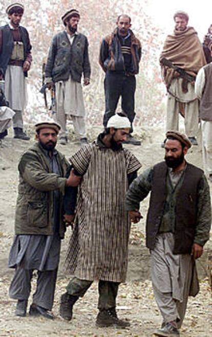 Dos <b></b><i>muyahidin</i> custodian a un preso árabe de Al Qaeda en Tora Bora.