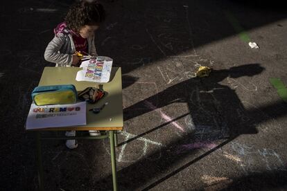 Una niña recorta un cartel contra los coches en un pupitre en la calle Vallehermoso, junto al colegio Fernando El Católico.