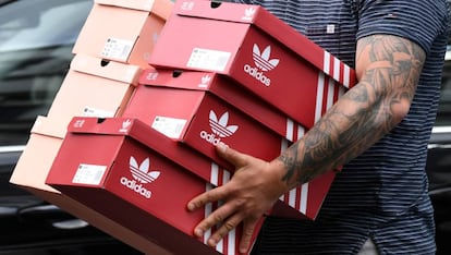 Un hombre carga con cajas de zapatillas Adidas tras salir de una tienda de la marca en Berlin, Alemania. 