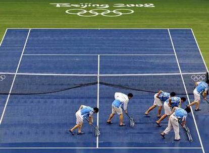 Voluntarios chinos limpian una pista de tenis.