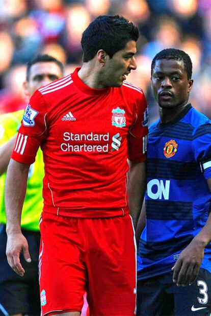 Luis Suárez y Evra, en segundo término, durante el duelo en Anfield.