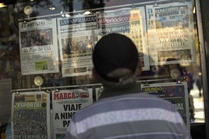 Un hombre observa las portadas de los periódicos de un quiosco de Barcelona.