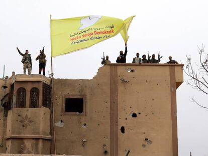 Combatientes de las Fuerzas Democráticas Sirias (FDS) ondean una bandera en Baguz,Siria. 