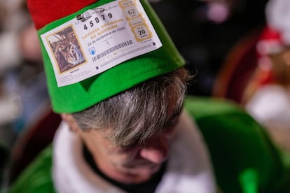 Una asistente muestra un décimo de la lotería antes de celebrarse el sorteo.