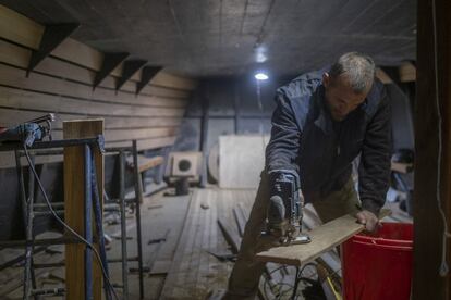 Un carpintero de ribera trabajando en la cubierta de popa, donde se colocará la caña del timón.