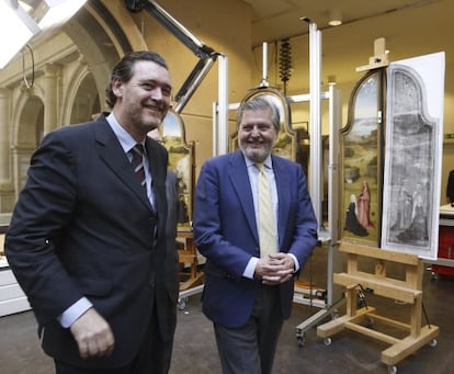 El ministro de Cultura, Iñigo Méndez de Vigo (derecha), y el director del Prado, Miguel Zugaza, pasan ante la obra 'La adoración de los Magos', del Bosco.