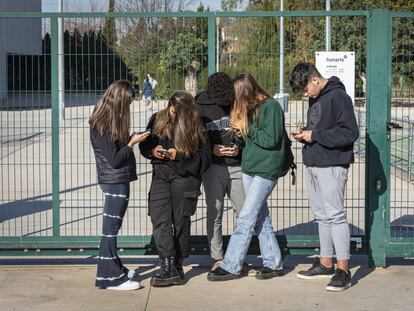 Adolescentes, en la puerta de un centro escolar en Valencia, con sus móviles.