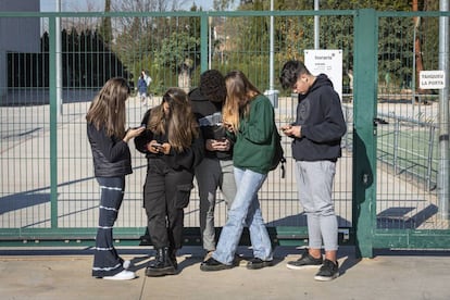 Adolescentes, en la puerta de un centro escolar en Valencia, con sus móviles.