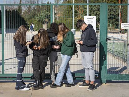 Adolescentes, en la puerta de un centro escolar en Valencia, con sus móviles.