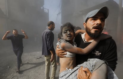 A Palestinian man carries a girl wounded in a shelling in Khan Younis in the southern Gaza Strip, October 26, 2023.