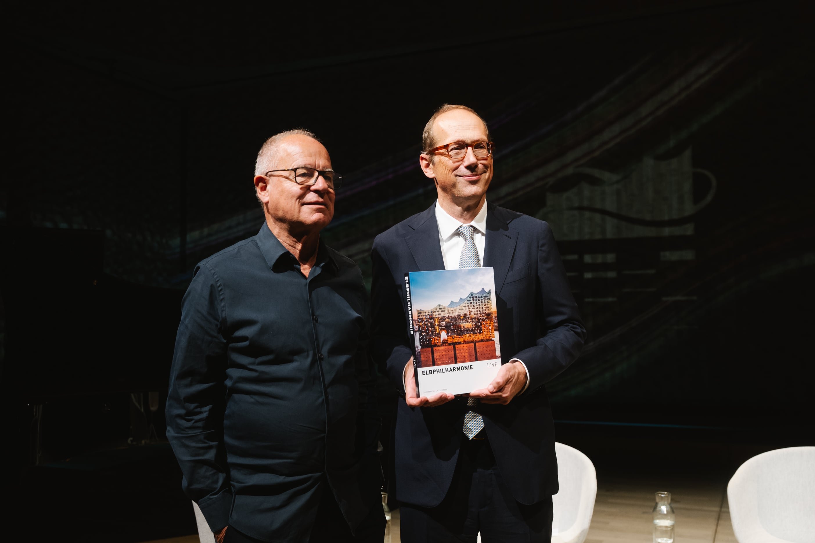 El arquitecto Pierre de Meuron y el intendente de la Elbphilharmonie Christoph Lieben-Seutter posan con el libro del décimo aniversario ‘Elbphilharmonie Live’, el 1 de septiembre en la Sala de Recitales.