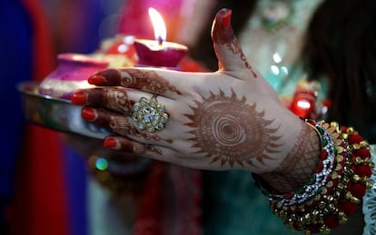 Una mujer casada sostiene una vela en un ritual para pedir longevidad y bienestar a su marido, este domingo en Jammu (India).