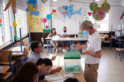 Un hombre vota rodeado de dibujos infantiles en el Colegio Público Alcazaba de Granada.