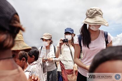 Un camión cargado de residuos llega hasta el basurero de Siem Reap (Camboya). Se estima que en este lugar trabajan unos 20 menores de edad con sus familias. Una turista japonesa tapada con una mascarilla hace fotos a los niños que trabajan en el basurero.