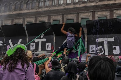 Una mujer se cuelga de una de las vallas instaladas afuera de Palacio Nacional durante la protesta del 8-M en Ciudad de México.