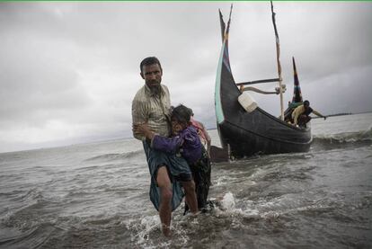 Un refugiado rohingya ayuda a una anciana a llegar a tierra tras encallar su bote de madera en el que huían de Myanmar, el 12 de septiembre de 2017, en Dakhinpara (Bangladés)