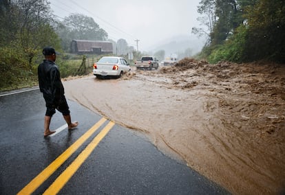 Un residente observa cómo los automóviles atraviesan un tramo peligroso de una carretera inundada en las afueras de Boone, (Carolina del Norte).