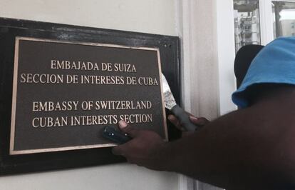 A worker removes the sign from the US Interests Section in Havana, which now functions as an official embassy.