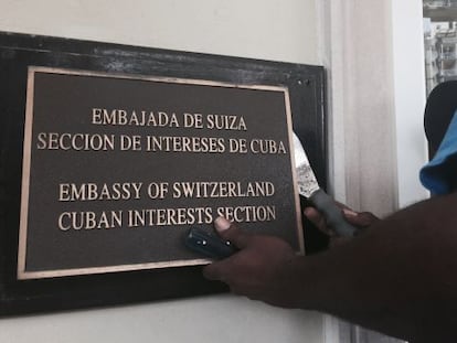 A worker removes the sign from the US Interests Section in Havana, which now functions as an official embassy.