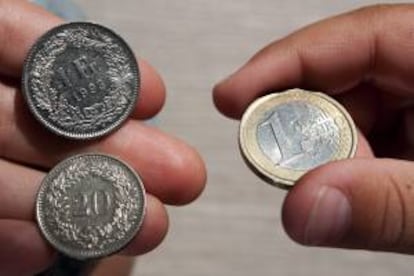 Una moneda de un franco y otra de 20 céntimos son colocadas junto a una moneda de un euro en Lausana (Suiza). EFE/Archivo