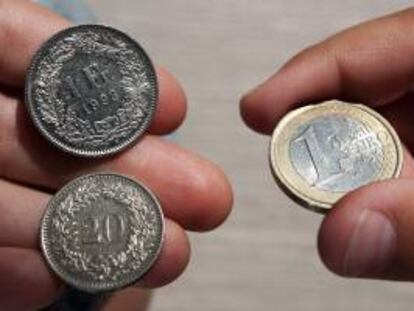 Una moneda de un franco y otra de 20 céntimos son colocadas junto a una moneda de un euro en Lausana (Suiza). EFE/Archivo