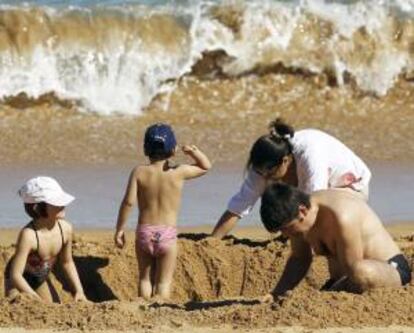 Una familia juega con la arena en la playa santanderina del Camello. EFE/Archivo