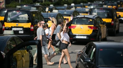 Turistas pasean por la Gran Vía de Barcelona,entre taxistas.