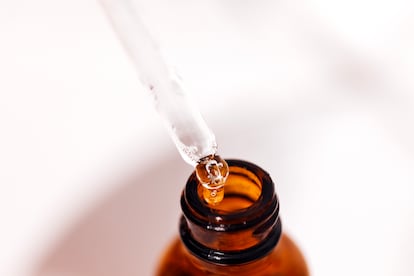 Un técnico de laboratorio introduce gotas de un producto químico en un frasco.