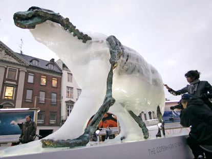 Los visitantes observan c&oacute;mo se derrite una escultura de un oso polar para mostrar un esqueleto de hierro. 