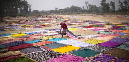 Una mujer recoge pañuelos de colores, antes tendidos, en Agra en India.
