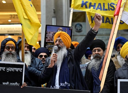 A demonstrator uses a microphone as others hold flags and signs as they protest outside India's consulate on September 25, 2023.