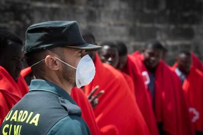 Seis días después del atraque del Aquarius a Valencia con 630 personas y la llegada de más de un millar de personas a las costas andaluzas en solo 48 horas, el desembarco masivo de pateras prosigue. En la imagen, un agente de la Guardia civil monta guardia mientras son atendidos inmigrantes en el puerto de Tarifa.