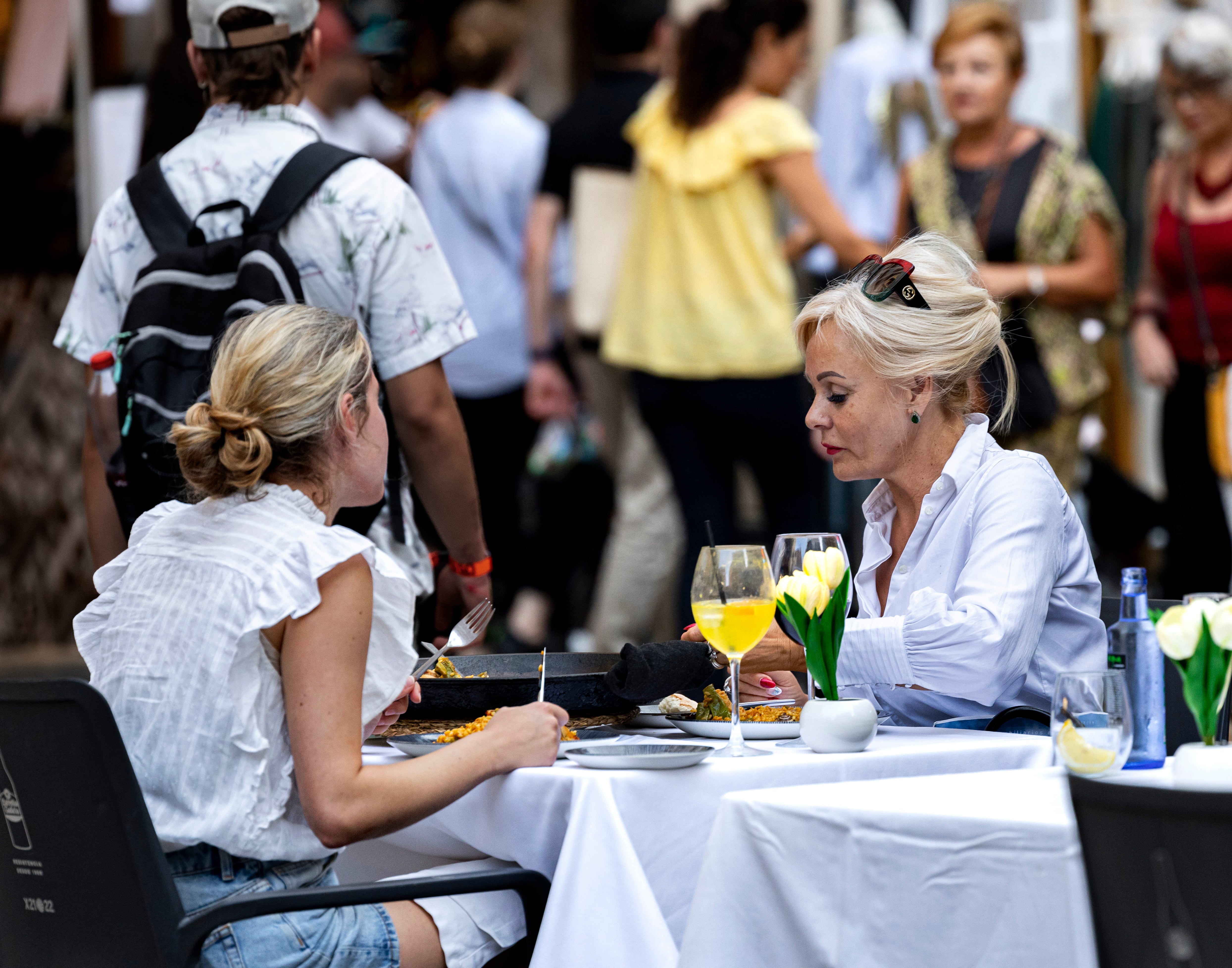Dos visitantes de Fallas, comiendo una paella en unas Fallas de València. 