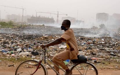 A man wears a mask as he rides a bike in a polluted street of Ouagadougou on December 3, 2015, in the  Sahelian country of Burkina Faso which is regularly hit by drought. / AFP / ISSOUF SANOGO