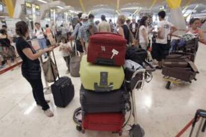 Decenas de pasajeros esperan con sus equipajes en la T4 del aeropuerto de Barajas. EFE/Archivo