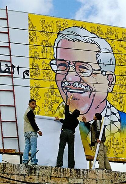Unos jóvenes palestinos colocan un cartel gigante con la cara de su nuevo presidente, Mahmud Abbas, en Ramala.