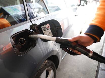 Un empleado de una gasolinera echa combustible a un coche.