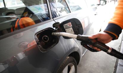 Un empleado de una gasolinera echa combustible a un coche.