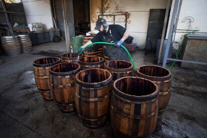 Un operario moja con agua los toneles que van a ser posteriormente trabajados con fuego. 