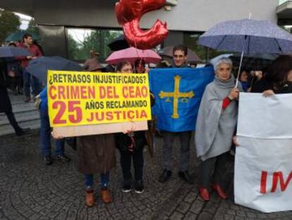 Familiares de los fallecidos en el crimen del Cash Record de O Ceao, con un cartel de protesta, y una bandera de Asturias, donde De Lara también investiga la corrupción.