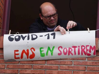 Un home penja un missatge de suport a la seva finestra.