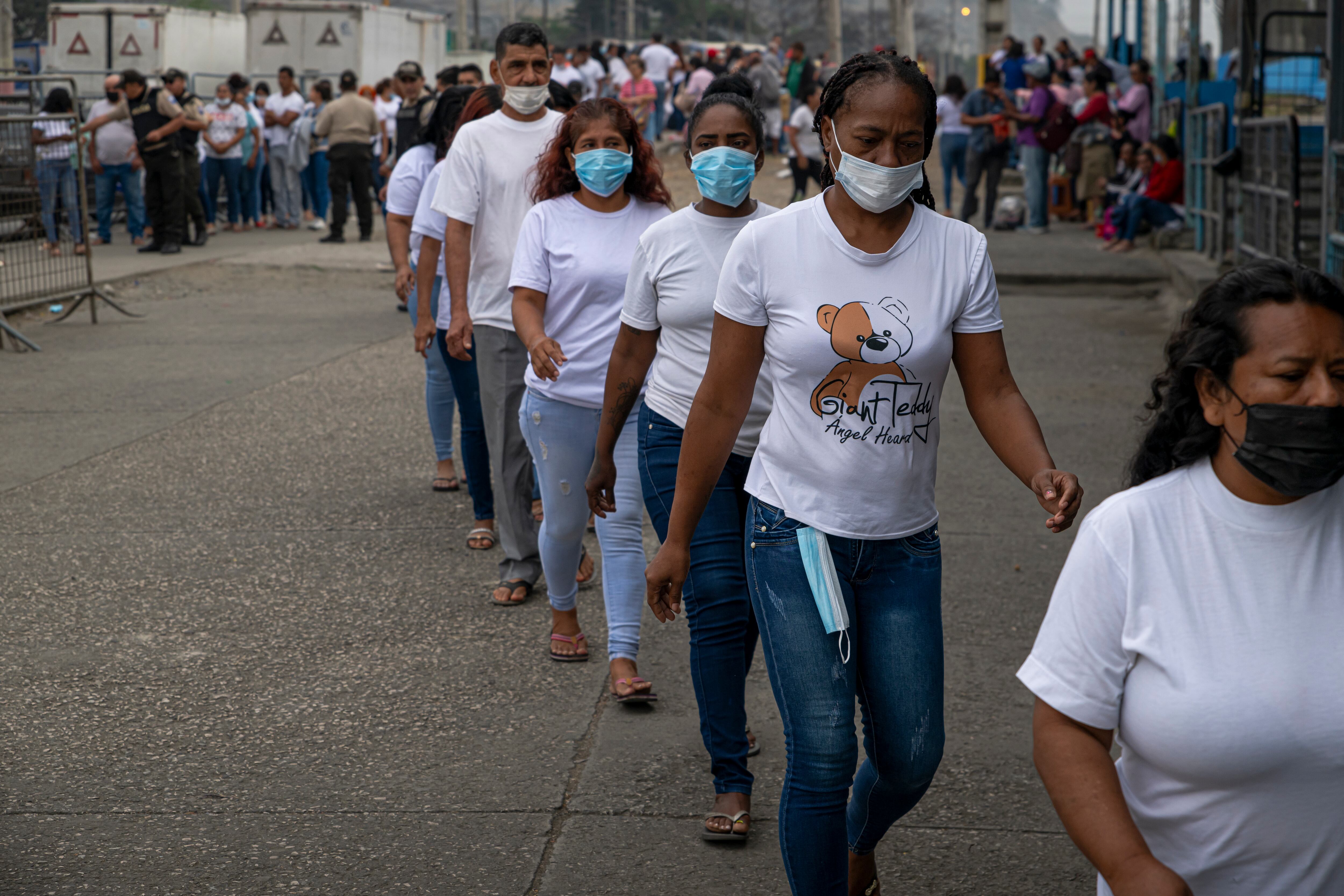 Familiares de las personas privadas de libertad hacen fila para ingresar a la Penitenciaría del Litoral, mientras agentes policiales verifican sus datos personales y los de la persona a visitar, en Guayaquil el 17 de julio.