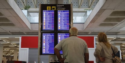 Pasajeros consultando vuelos en el aeropuerto de Palma de Mallorca.