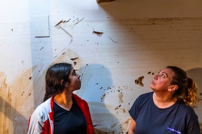 Pilar Pérez, dueña de la peluquería Azabache, y su hija Noelia, miran la marca que indica hasta dónde llegó el agua el día de la riada. 