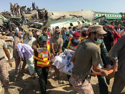 Miembros de los equipos de rescate trasladan el cuerpo de una de las víctimas de la colisión de dos trenes en Ghotki, Pakistán, este lunes.