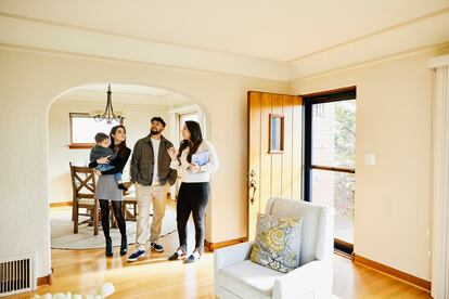 Familia con un niño pequeño en conversación con un agente de bienes raíces mientras busca una casa en venta.