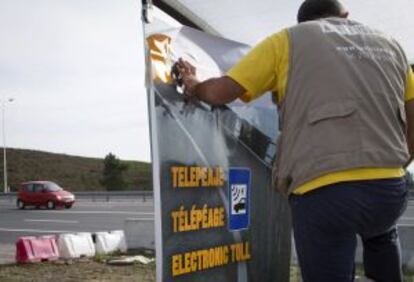 Un operario coloca un cartel informativo en el paso fronterizo de Ayamonte (Huelva)