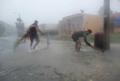 Dos hombres recogen ramas de una calle de Fajardo (Puerto Rico), el 6 de septiembre. 