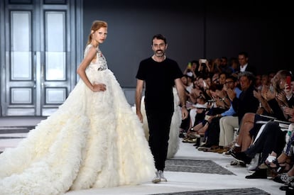 El diseñador Giambattista Valli, en la pasarela junto a una de sus modelos al finalizar su desfile de alta costura.